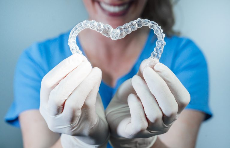Female Doctor Holding Two Transparent Heart Shaped Dental Aligners